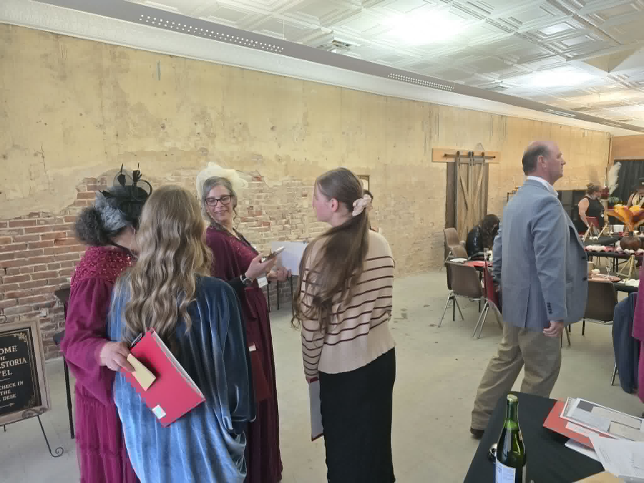 Costumed guests comparing notes and red case folders during the investigation.