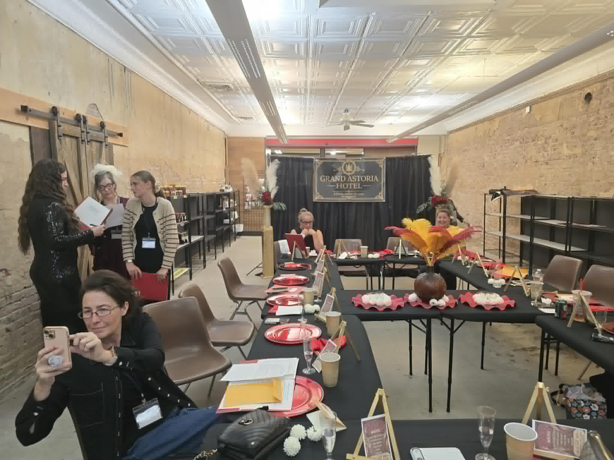 Red place settings, clue packets, and the Grand Astoria Hotel banner before dinner begins.